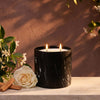 Black marble-pattern candle jar with two lit wicks and cream-colored wax