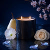Black marble-pattern candle jar with two lit wicks reflected on glossy surface