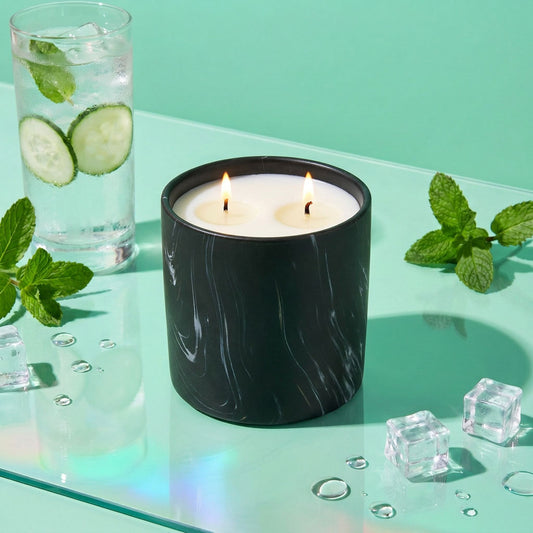 Black marbled jar candle with two flames and white wax on glass tray