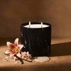 Black marbled jar candle with two flames and white wax, angled view
