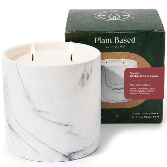 White marble pillar candle with two flames beside plant-based candle box