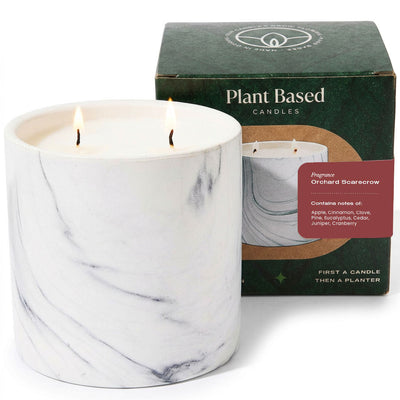 White marble pillar candle with two flames beside plant-based candle box