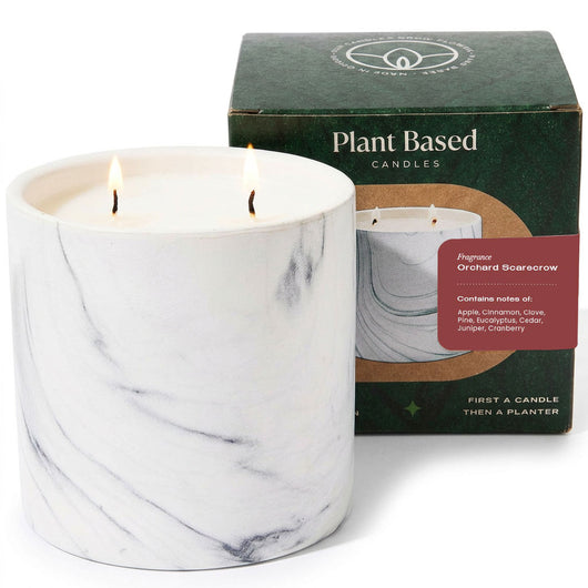 White marble pillar candle with two flames beside plant-based candle box