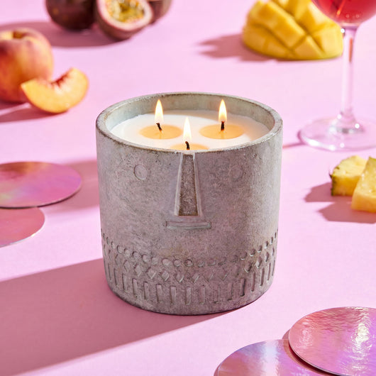 Gray stone-textured jar candle on tabletop with four burning wicks
