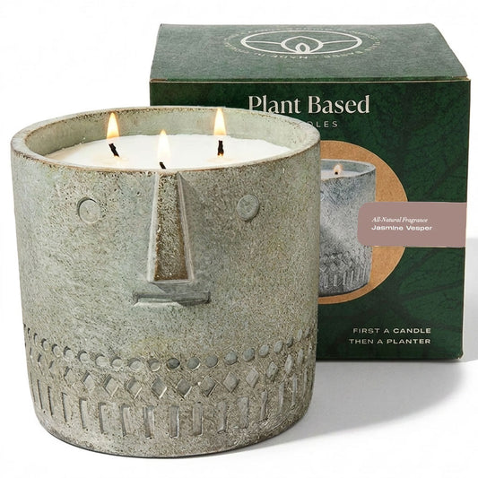 Gray stone-look face candle in round container with four lit wicks and etched pattern