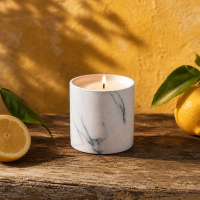 White marble-effect candle with gray veining and lit wick