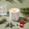 Lit white marble scented candle with yellow flame on top.