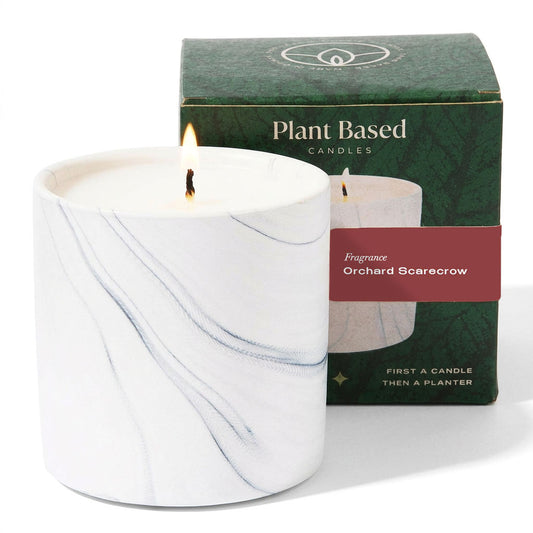 White marble-style candle in a glass jar with lit wick