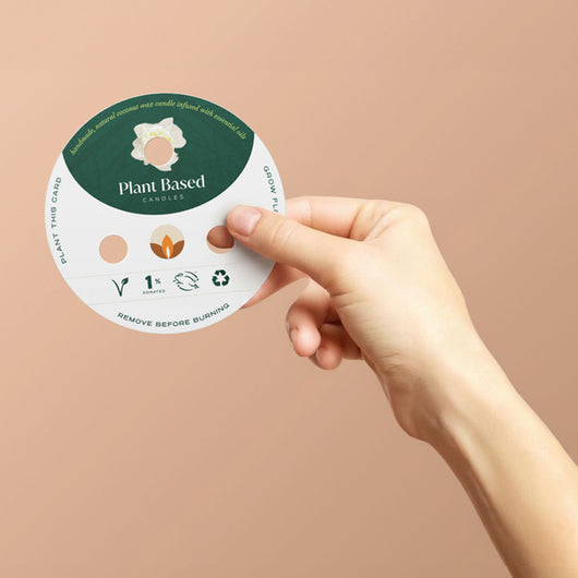 Plant-based candle label disc held by hand, with icons and “Remove before burning” note.