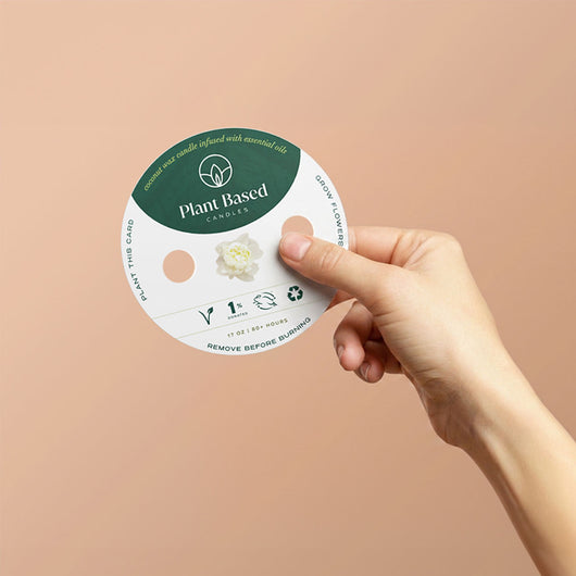 Green Plant Based circular label on packaging held by hand, candle jar visible.