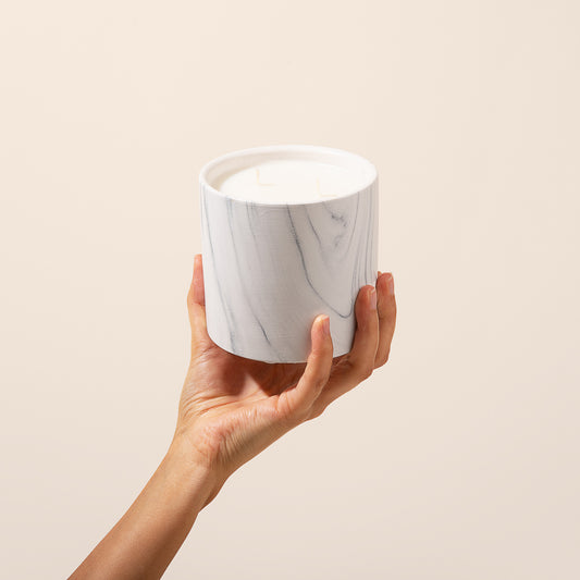 Marble-pattern candle jar with two wicks, held in hands