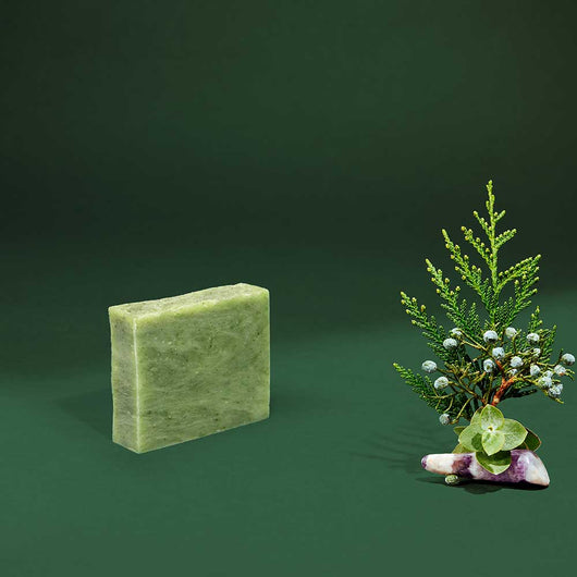 Rectangular organic soap bar, pale green, with a fresh botanical arrangement nearby